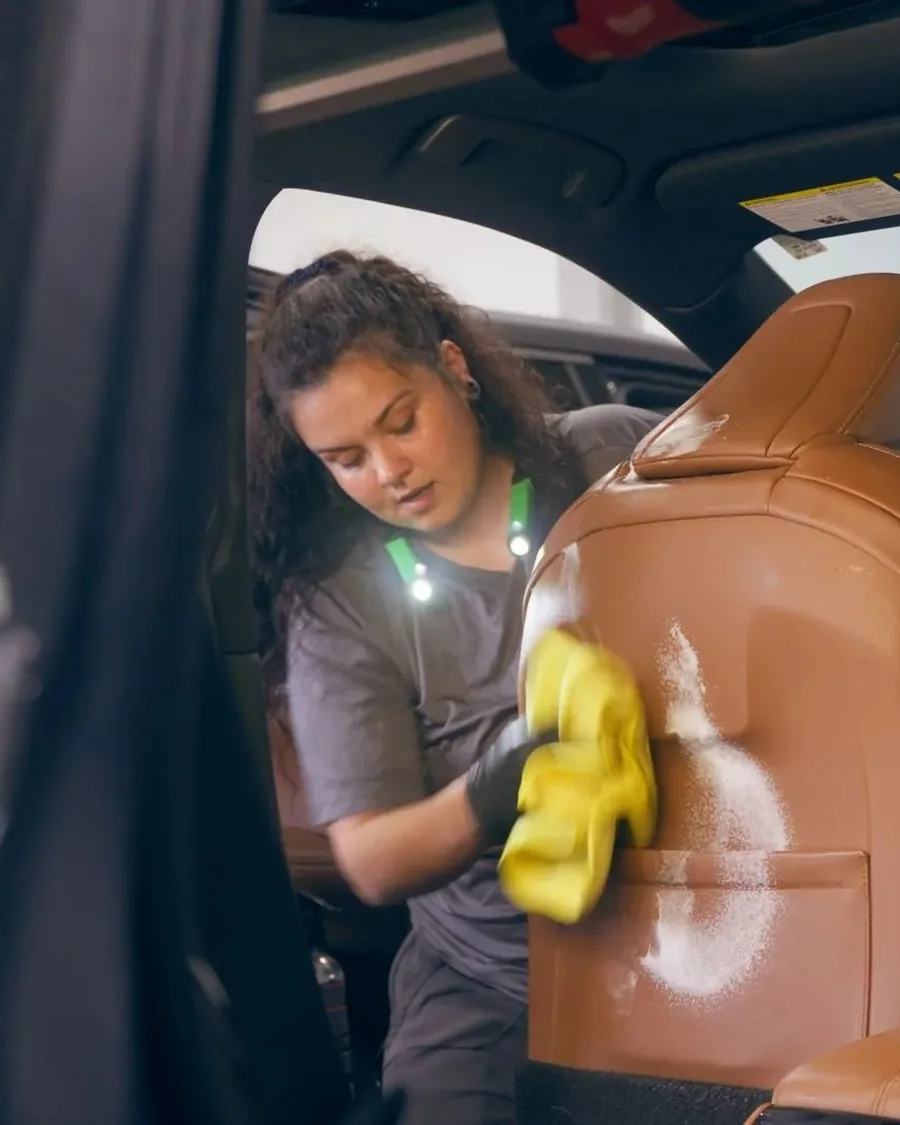 Detailer cleaning a leather seat inside a vehicle